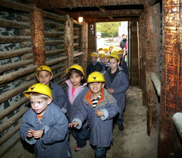 Kinder in Bergmannskleidung unterwegs im Stollen der Zeche Knirps