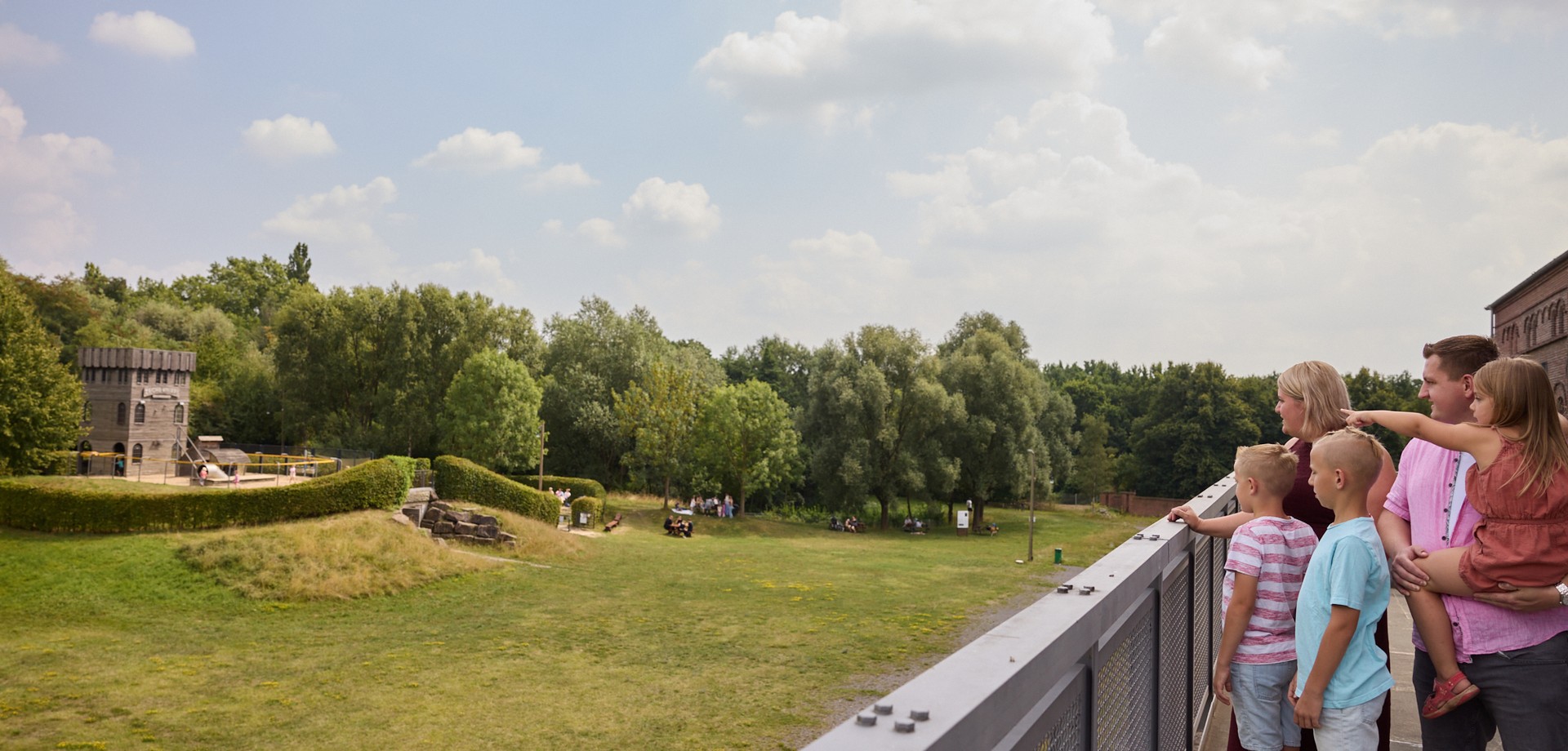 Familie blickt steht auf der Plattform am Malakowturm und schaut auf das Zechengelände mit dem Spielplatz