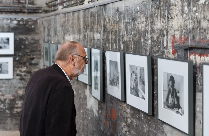 Ein Mann sieht sich Fotografien an, die an einer Wand im Malakowturm hängen