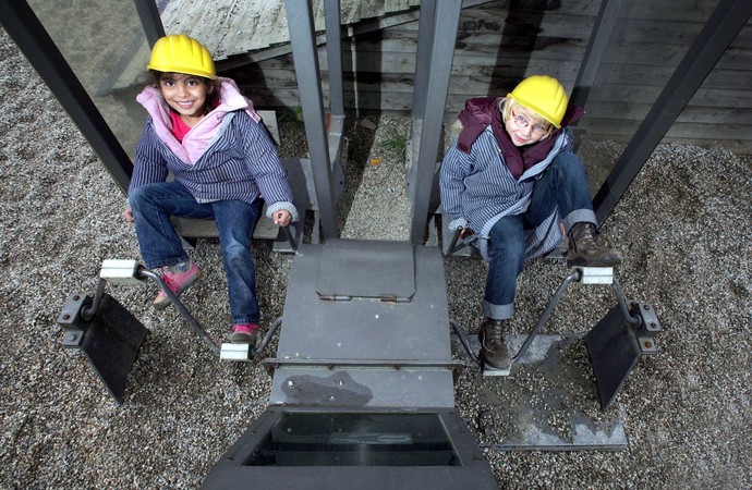 Zwei Kinder in Bergmannskleidung treten in die Pedale der Fördermaschine von Zeche Knirps
