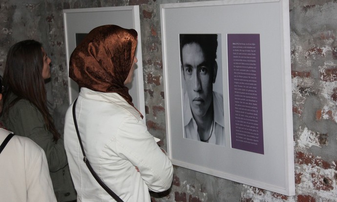 Eine Frau mit Kopftuch sieht sich Fotografien einer Ausstellung an.