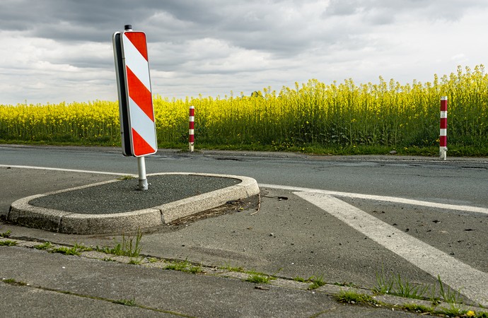 Straße mit einer Verkehrsinsel, auf der eine rote-weiße Barke steht. Im Hintergrund ein Rapsfeld. Foto: Udo Kreikenbohm