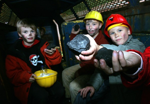 Kinder mit Helm halten Stücke Kohle in die Kamera