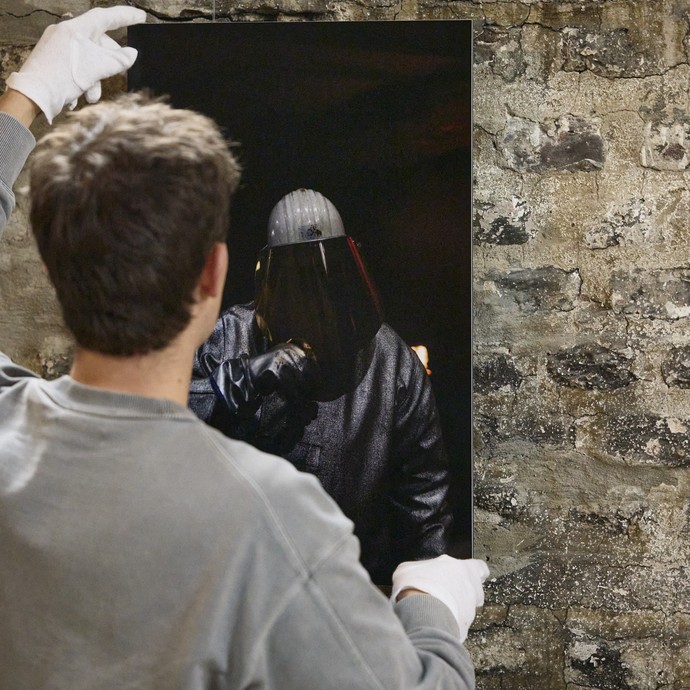 Der Fotograf Khalil Noé Döring hängt eine seiner Fotografien auf (vergrößerte Bildansicht wird geöffnet)