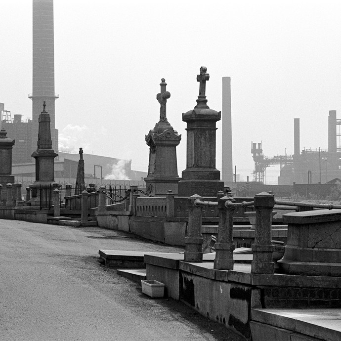 Ein Friedhof vor dem Hintergrund einer Industrielandschaft. (vergrößerte Bildansicht wird geöffnet)